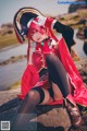 A woman in a pirate costume sitting on a rock by the water.