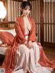 A woman in a red and white kimono sitting on a bed.