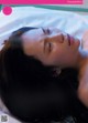 A woman laying on top of a bed next to a pillow.