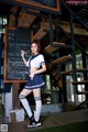 A woman in a school uniform posing in front of a blackboard.