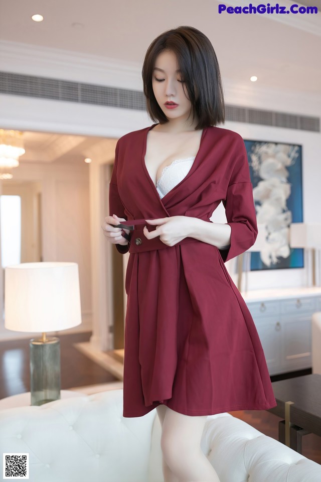 A woman in a red robe is standing in a living room.