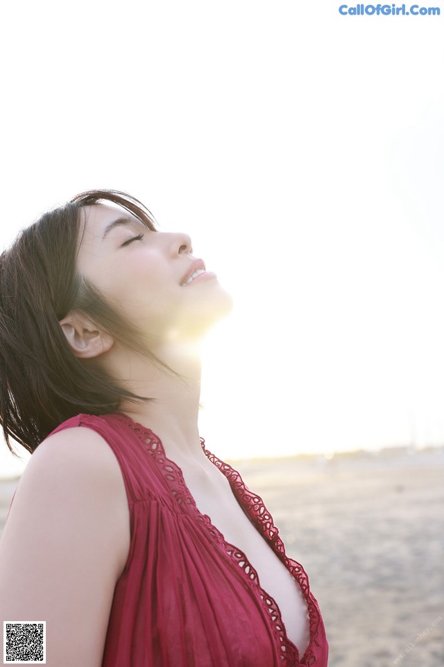 A woman in a red dress standing on a beach.