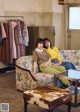 Two women sitting on a couch in a clothing store.